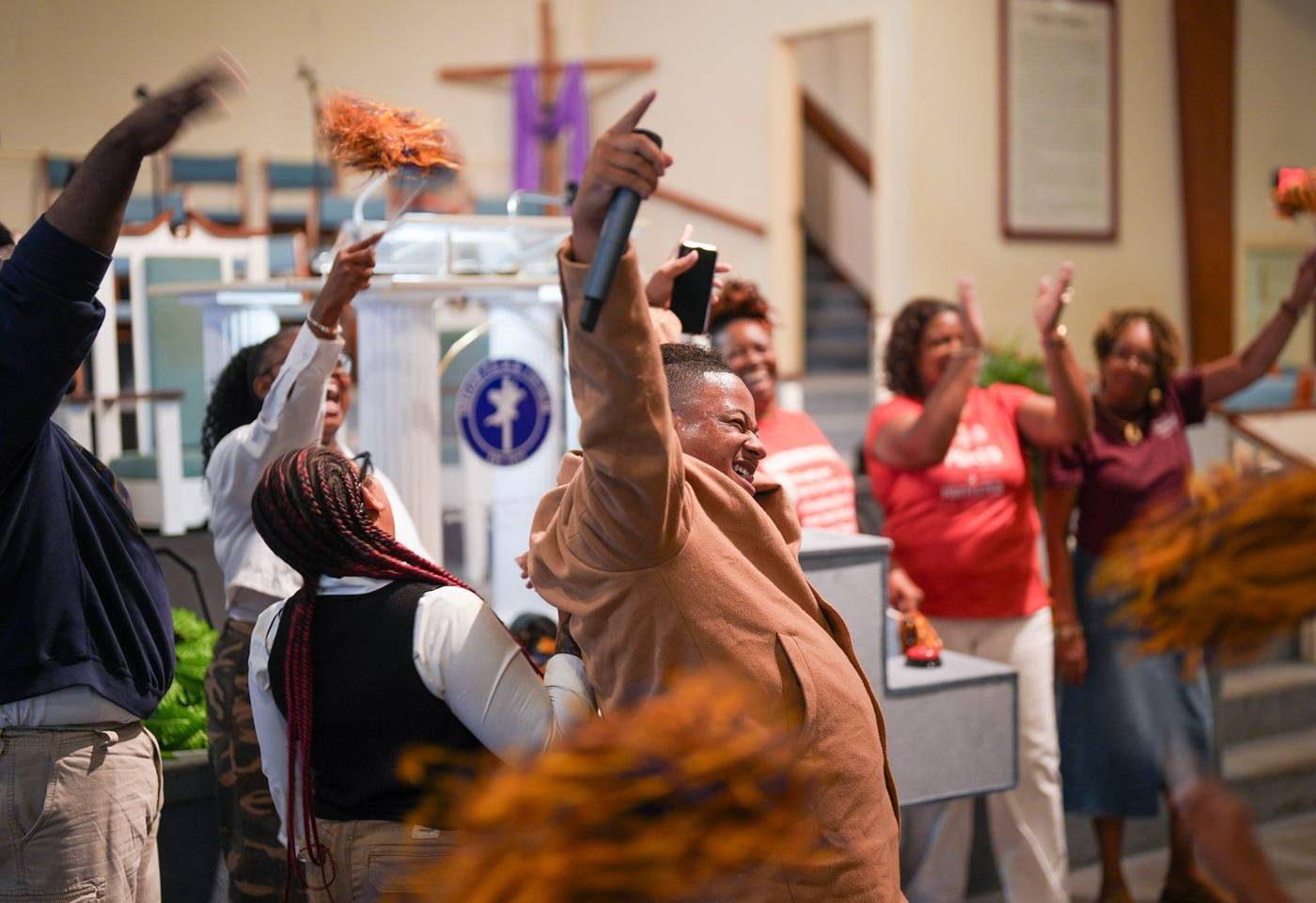 Members lifting hands and pom-poms in praise