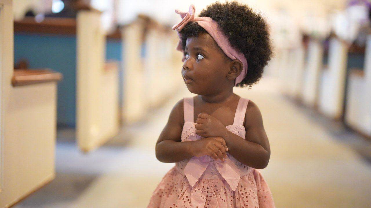 A little girl in a pink dress standing in the sanctuary aisle