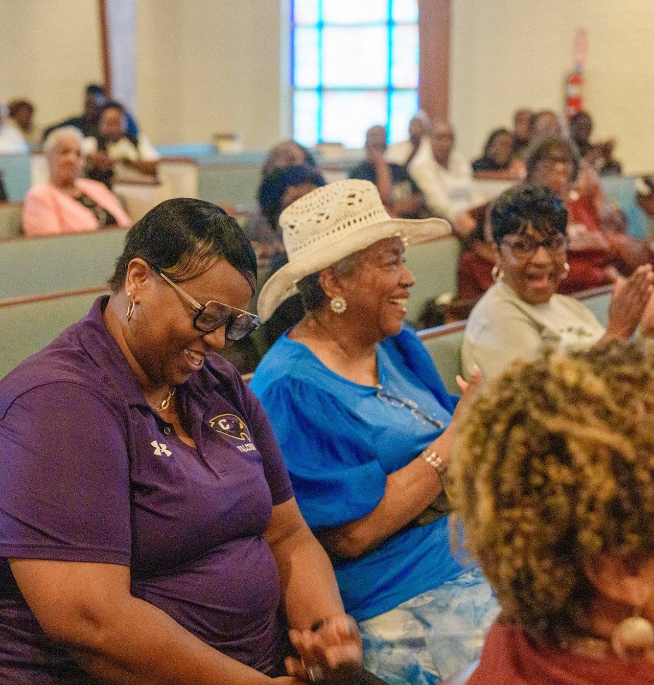 Two church mothers laughing together in the pews